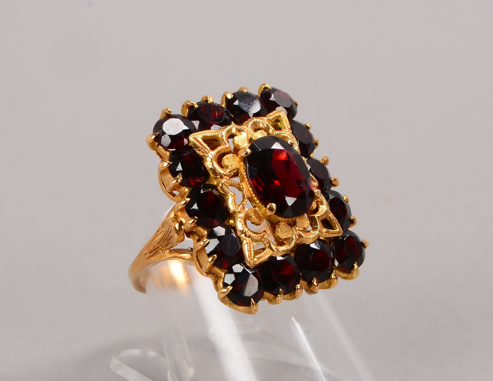 Ring, 750 GG (gestempelt), mit einem zentralen Granat, Stein im Ovalschliff, mit Granat-Entourage