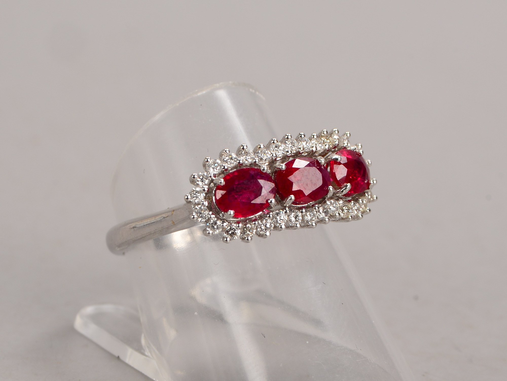 Ring, 750 WG (gestempelt), mit 3-fachem Rubinbesatz, im Ovalschliff, mit Diamanten-Entourage