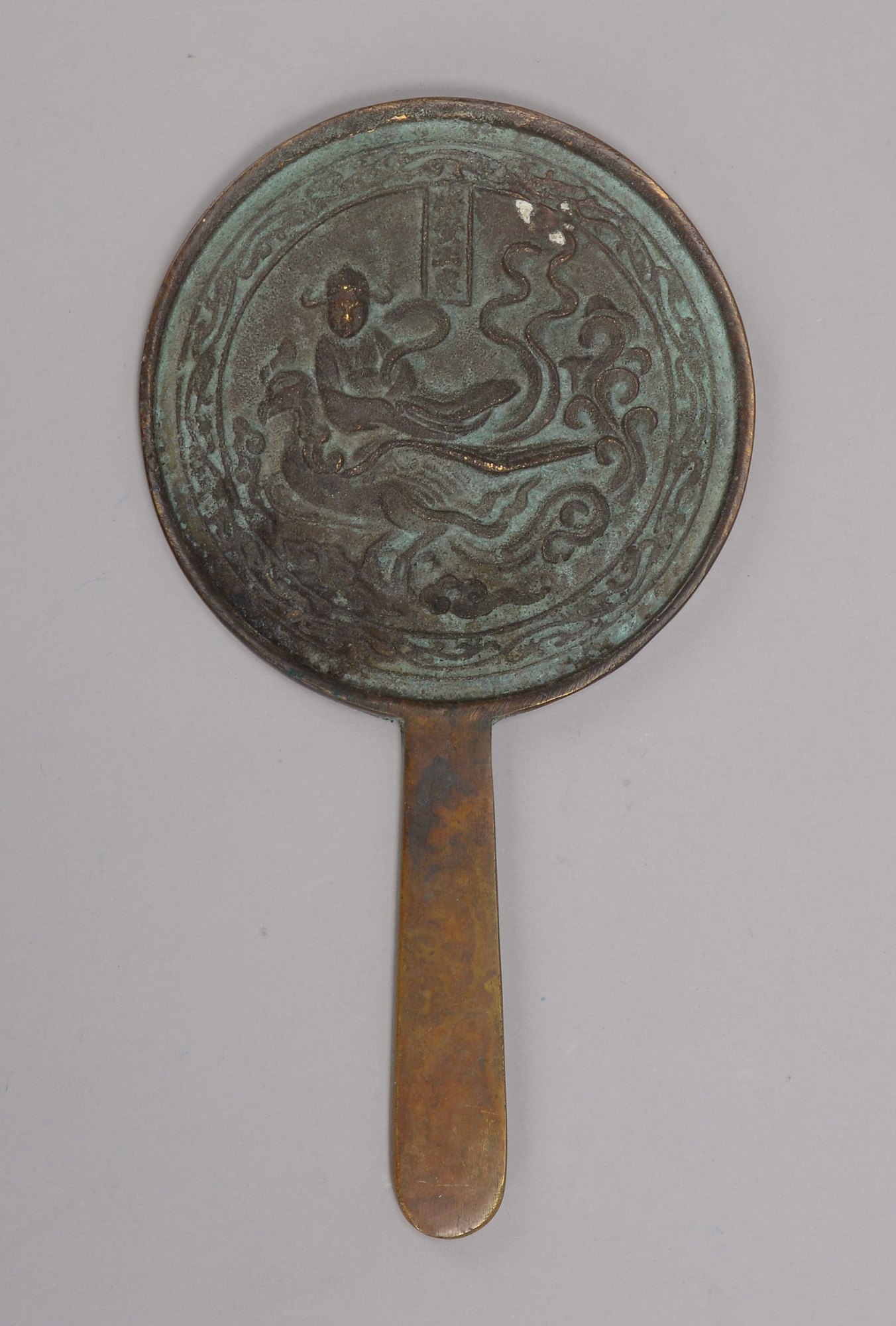 Handspiegel (China), Bronze, mit Reliefdekor ('Buddha auf Fantasievogel'); Höhe 20,5 cm, Ø 11 cm