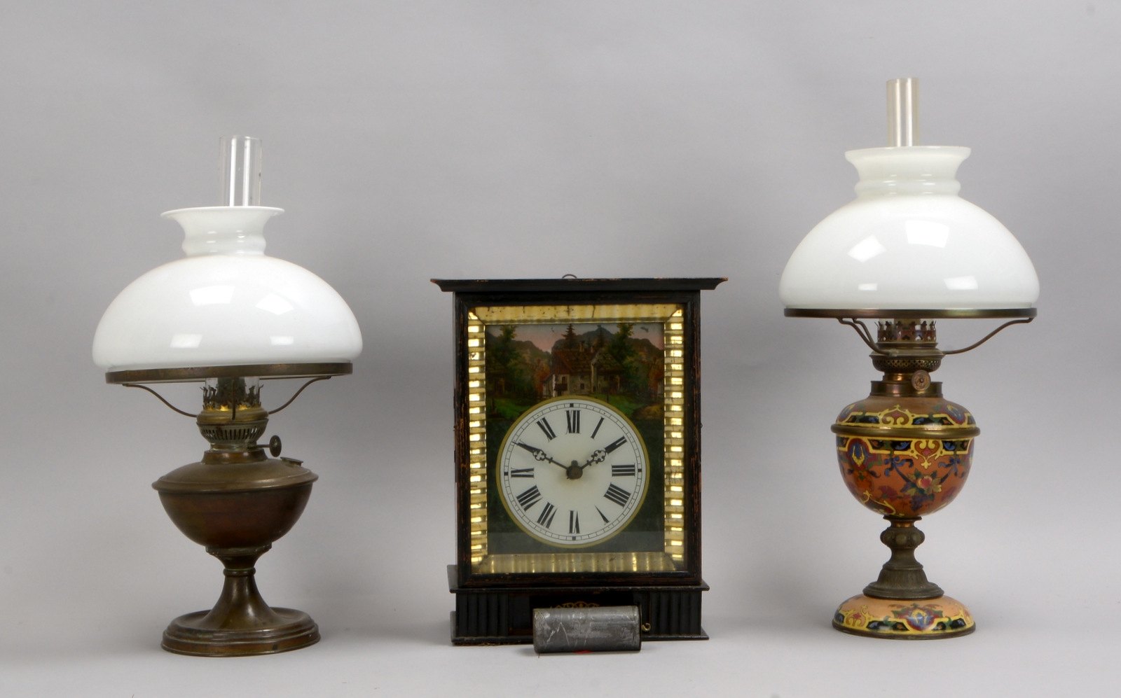 2 Petroleumlampen, versch. Ausf., 1x Keramikfuß/1x Messingfuß; und 1 Wanduhr