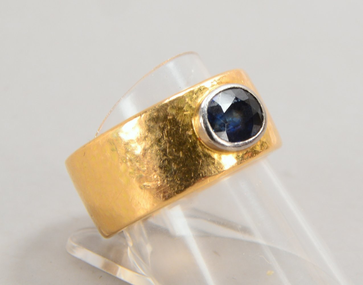 Designerring, 750 GG (gest.), massiv, Hammerschlag-Dekor, mit fac. ovalem Saphir