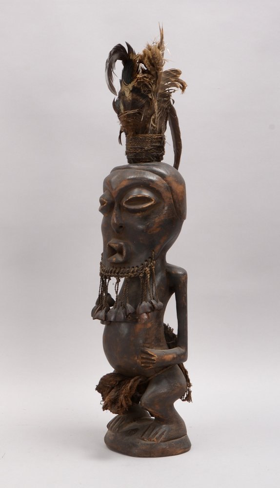 Holzskulptur (Benin), 'Hockender Mann' - mit Vogelfedern/Nussschalen-Behang