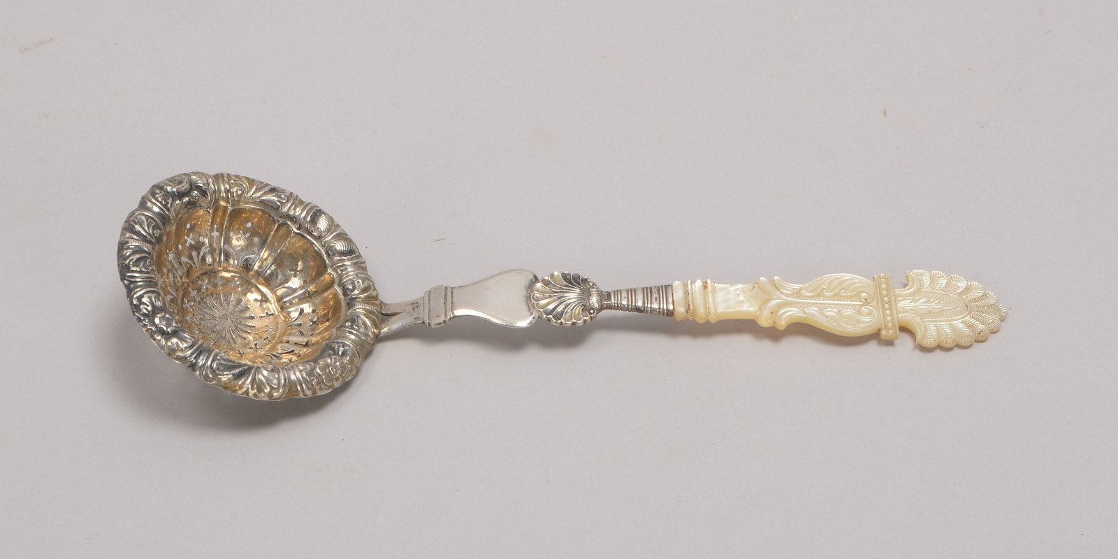 Teesieb, Silber, relief. Dekor, Reste von Vergoldung, mit Perlmuttgriff; Gew. 40 g