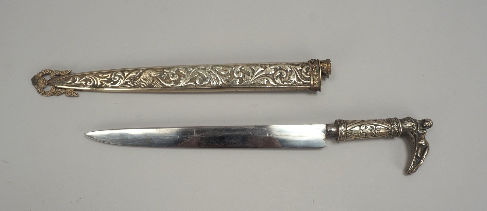 Dolch, 1-schneid. Klinge, Griff/Scheide mit flor. Reliefdekor, Griff mit plast. Darst.