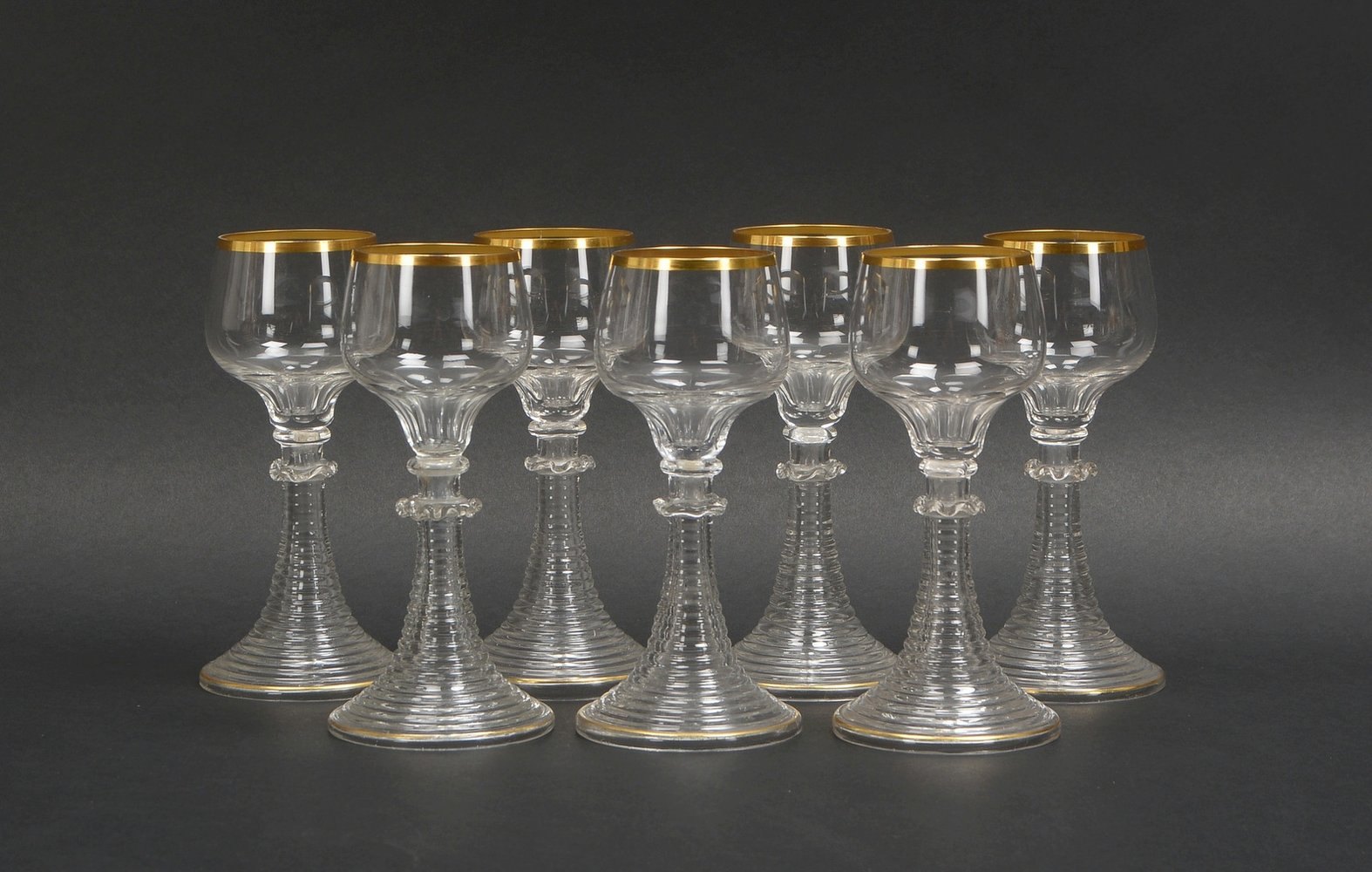 7 Weingläser, Klarglas, Kuppa mit Goldrand, getreppter Fuß; Höhe jew. 16,5 cm