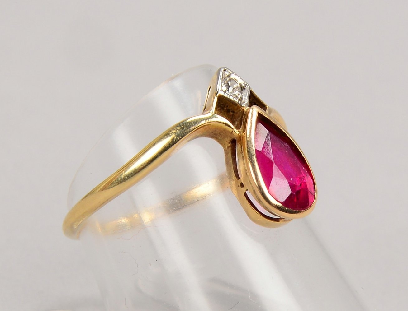 Ring, 585 GG (gest.), mit kl. Brill. sowie mit kl. Rubin im Tropfenschliff; Gew. 2 g