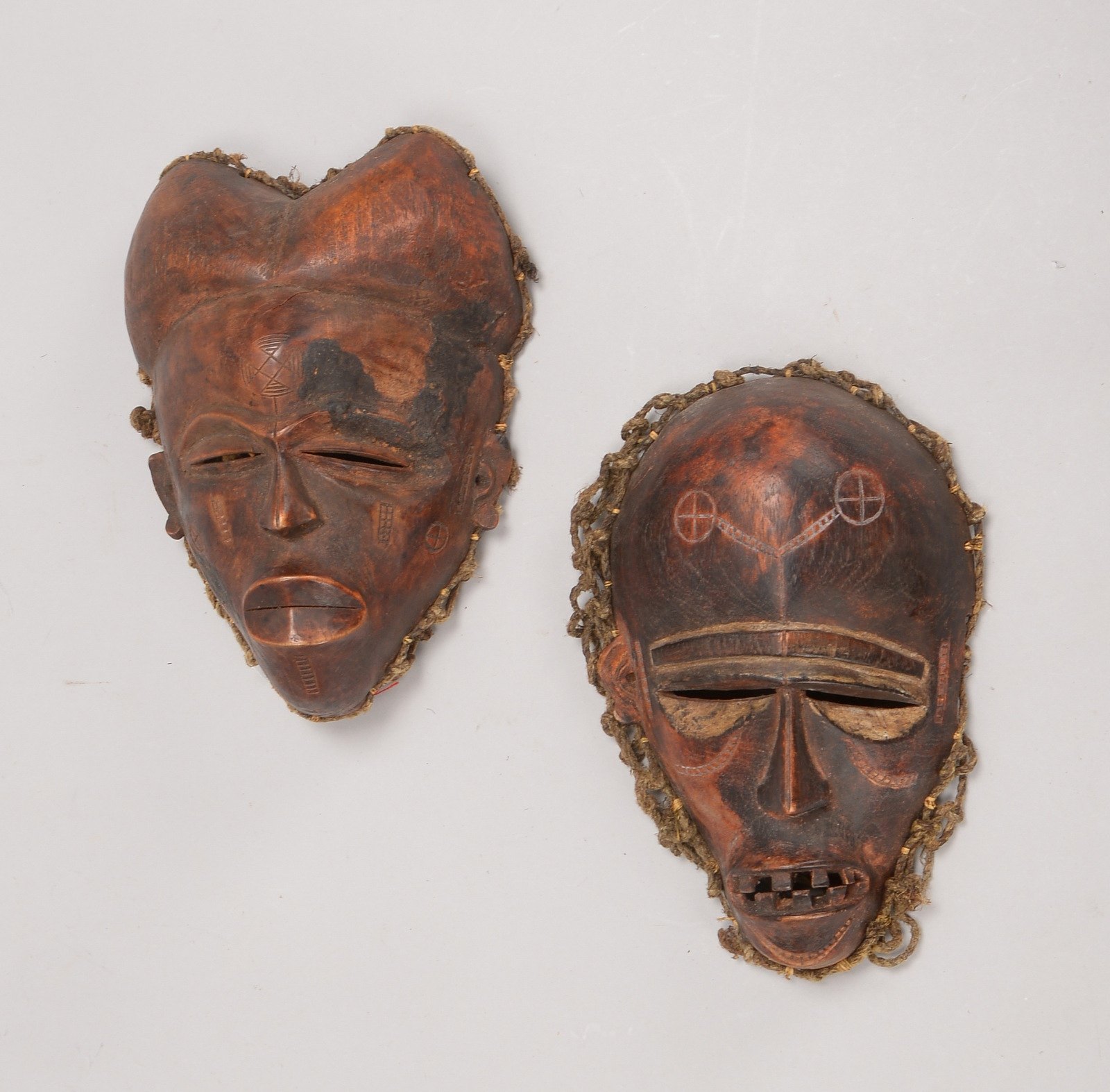 2 Tanz-/Ritualmasken, 'Männerköpfe', rötl. gebeiztes Holz, mit netzartiger Kopfbed.