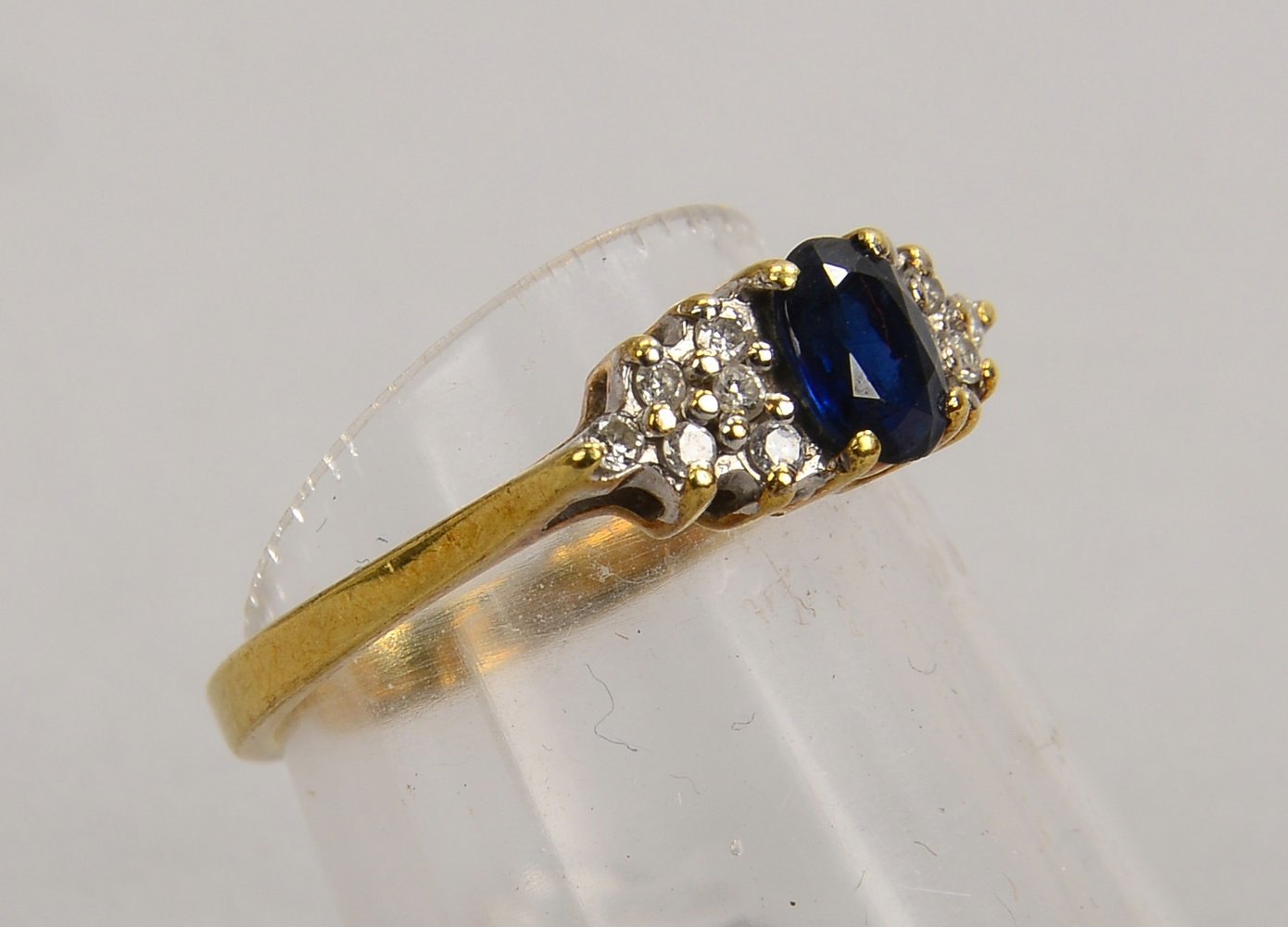 Ring, 585 GG (gest.), mit fac. ovalem Saphir und 12x kl. Diam.; RG 52, Gew. 2,50 g