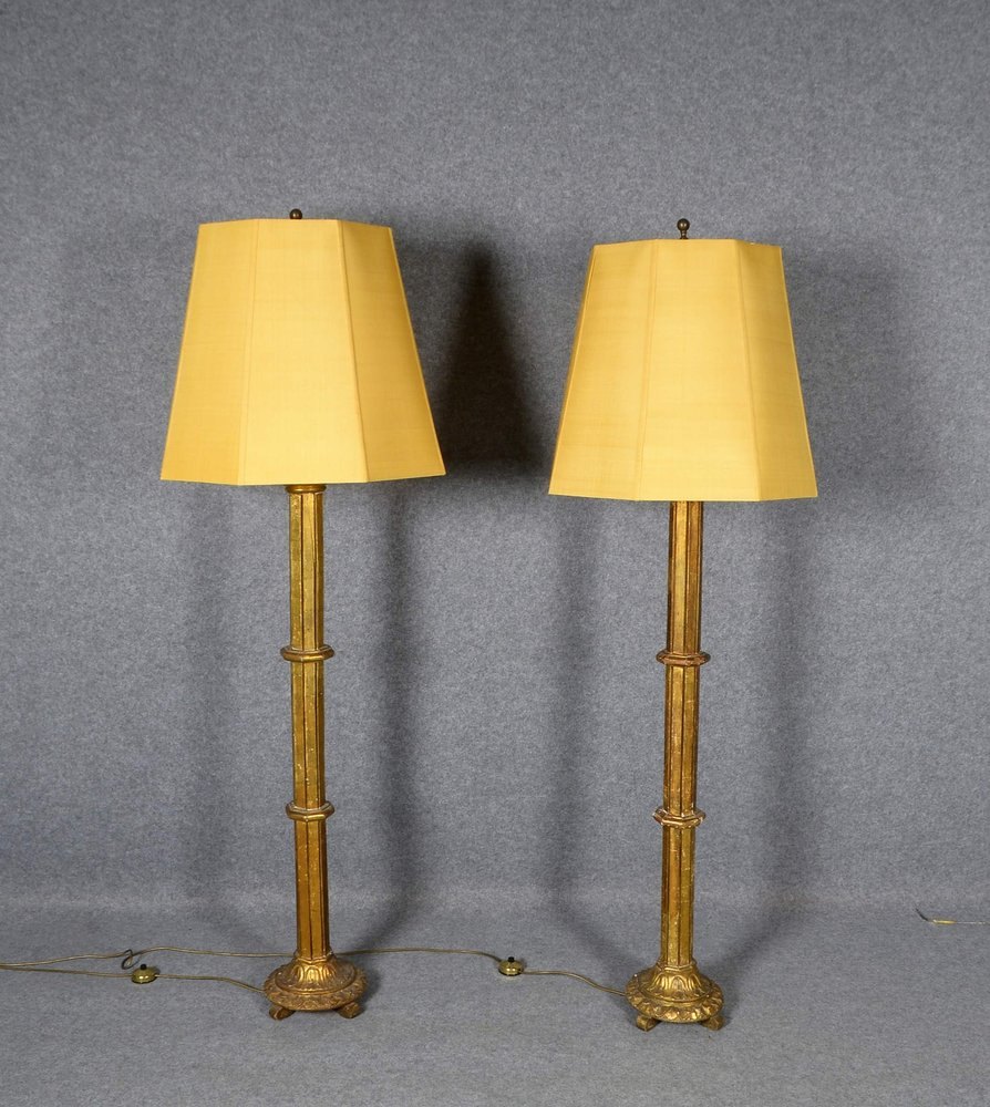 2 Stehlampen, je 2-fl., kannel. Holzsäulen auf Lotusfuß, goldstaff., je 2x Wildseide-Schirme
