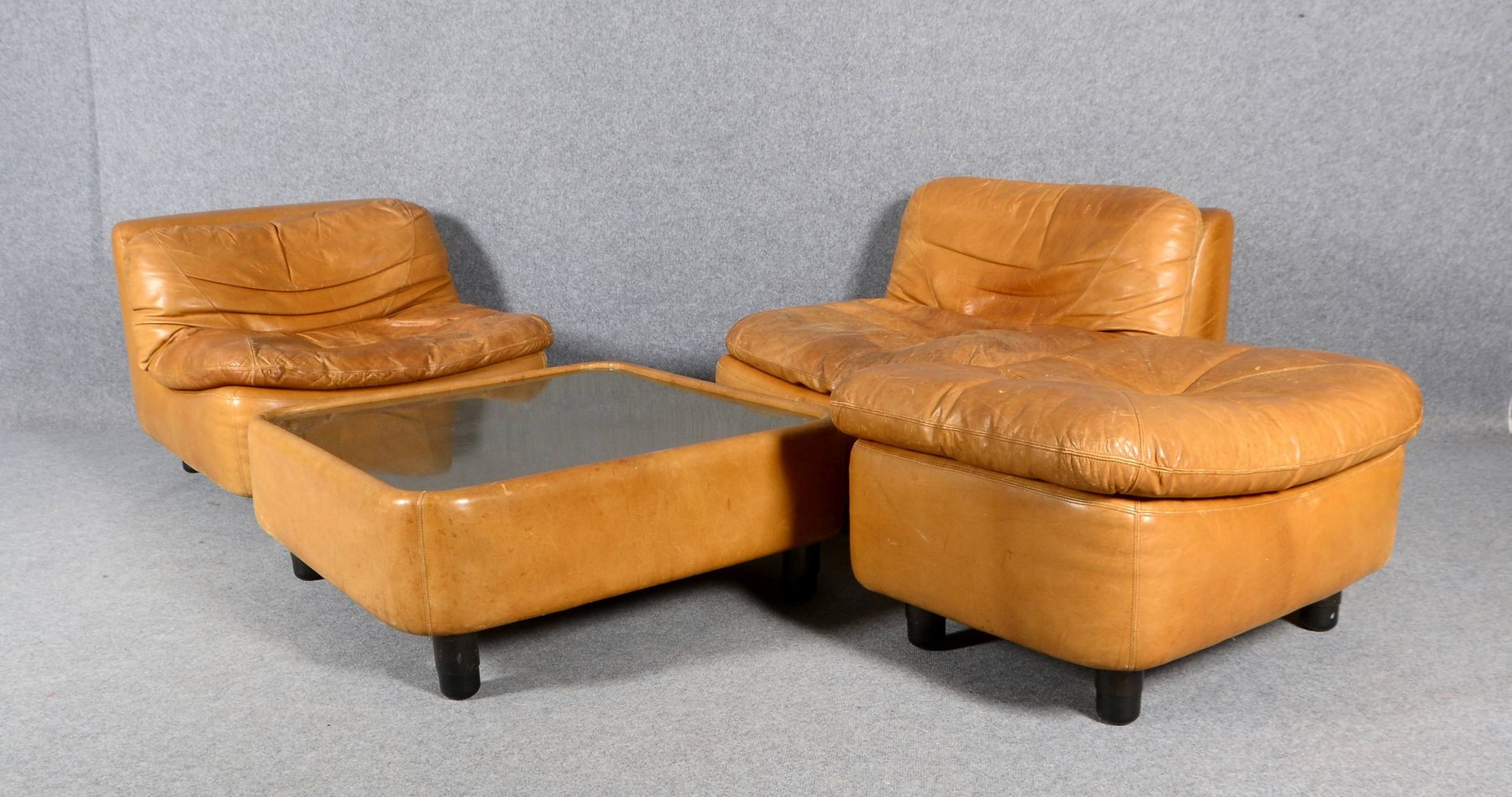 2x Sessel, cognacf. Leder, mit Fußhocker; und Couchtisch, mattierte Edelstahlplatte