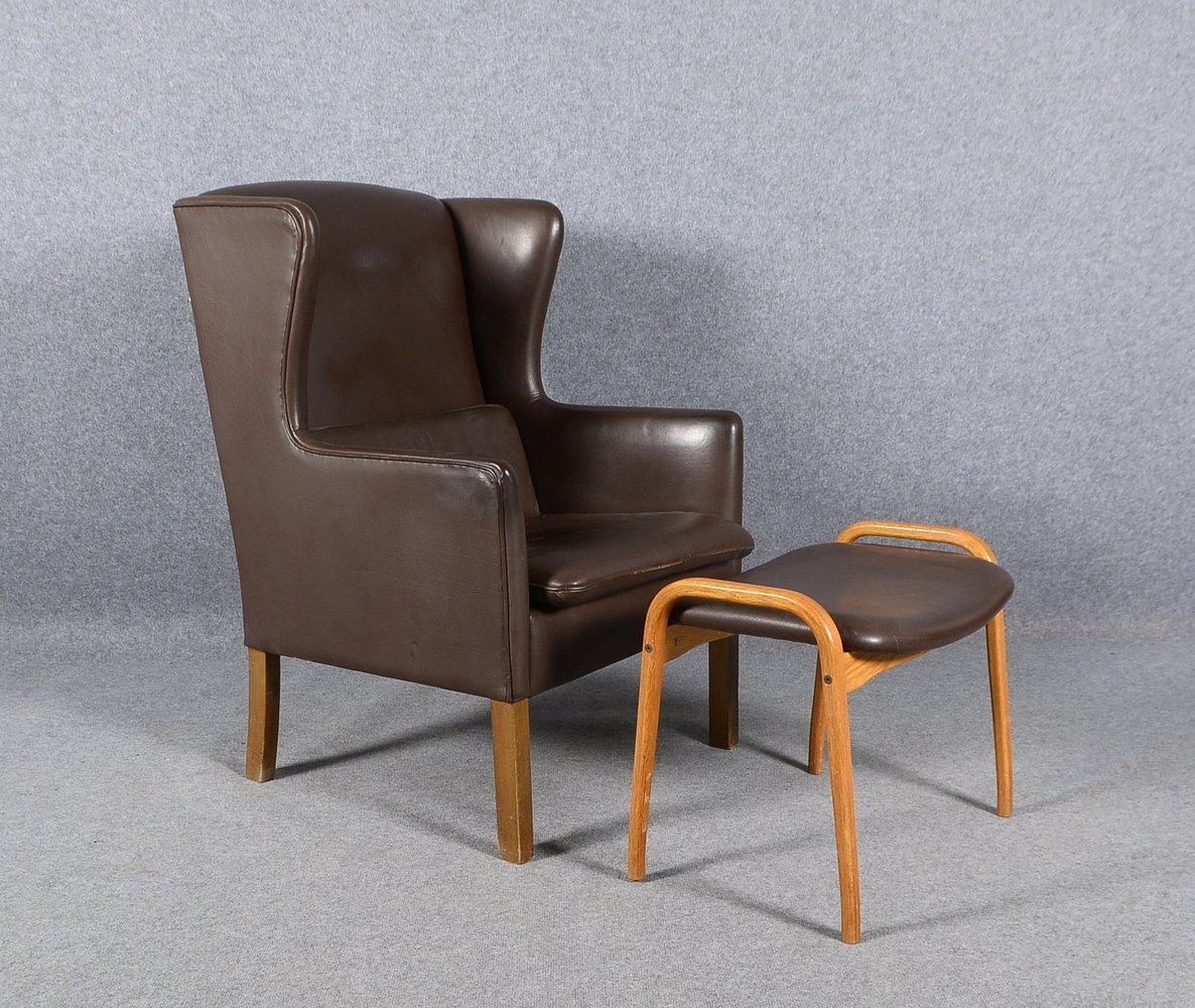 Ohrenbackensessel, dän. Design, Büffelleder, Lehnhöhe 108 cm; anbei ein Fußhocker