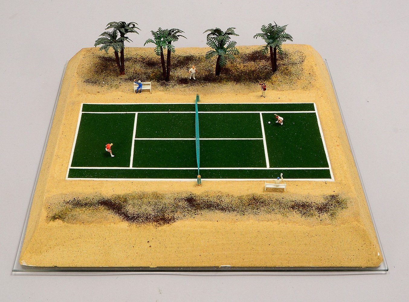 Sport-Diorama, 'Tennis-Court', mit Spielerfiguren und Palmensaum, auf Glasplatte; Maße 37 x 37 cm
