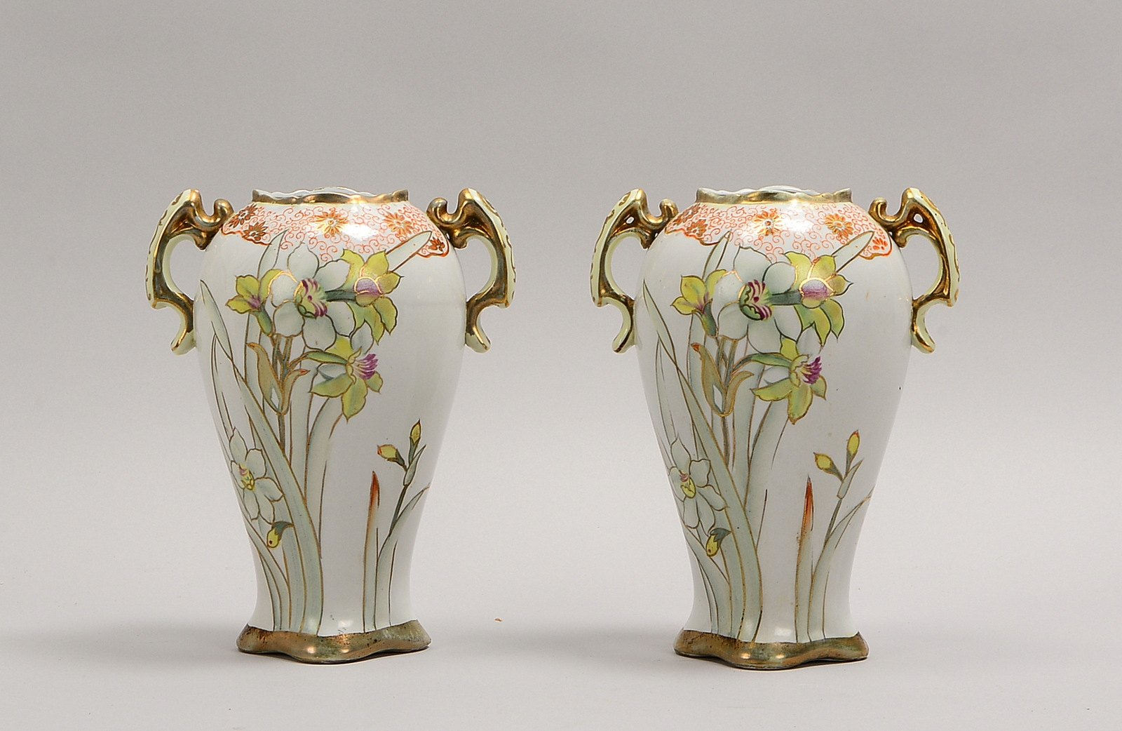 2 Porz.-Henkelvasen (um 1910), polychr. bem., goldstaff., im Boden gem.; Höhe 22 cm
