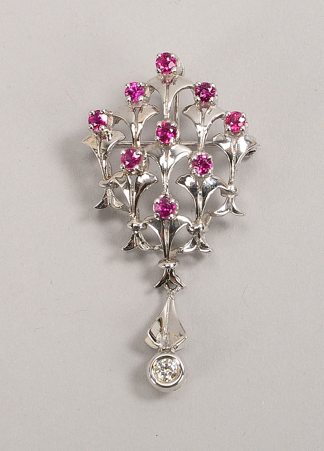 Anh./Brosche, 585 WG (gest.), mit Brill./ca. 0,18 ct, und 9x Rubinen/ca. 1,08 ct; Gew. 7,20 g