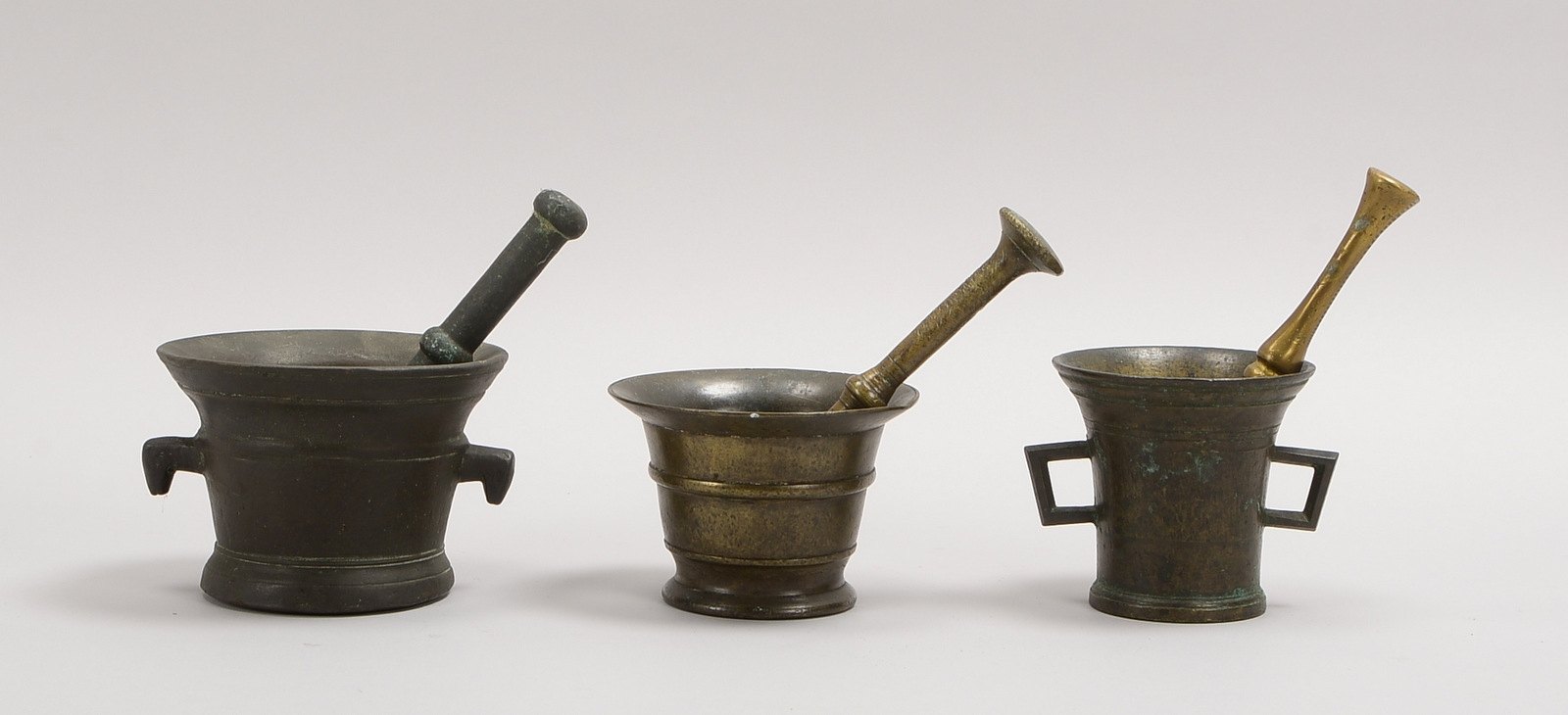 3 Bronzemörser, versch. Ausf., jew. mit Pistill; Höhe bis 10 cm, Länge Pistill: bis 19 cm