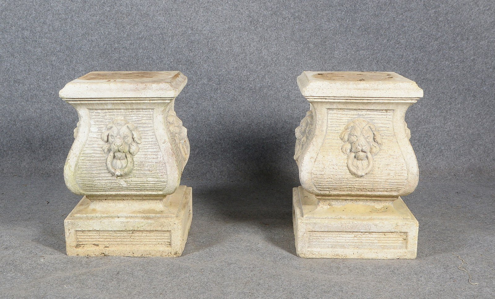 Paar Steinguss-Postamente, umlaufend mit 'Löwenkopf'-Reliefs; und Kunstst.-Puttofigur