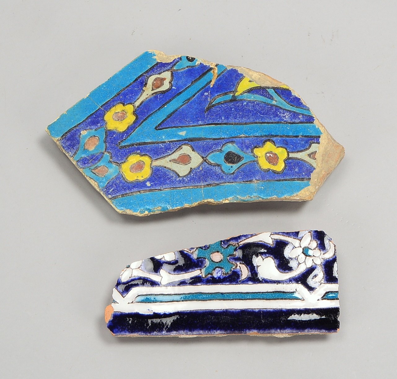 2 Kachelfragmente (islam.), glasiertes Steinzeug; Maße 25 x 15 cm/18 x 18 cm