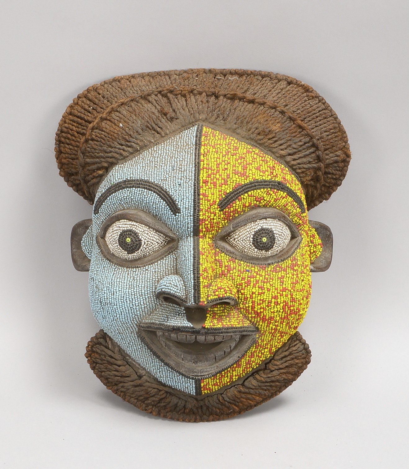 Ritualmaske, Holz mit Perlenbesatz, mit Rattan-'Kopfbehaarung'; Maße 40 x 30 cm