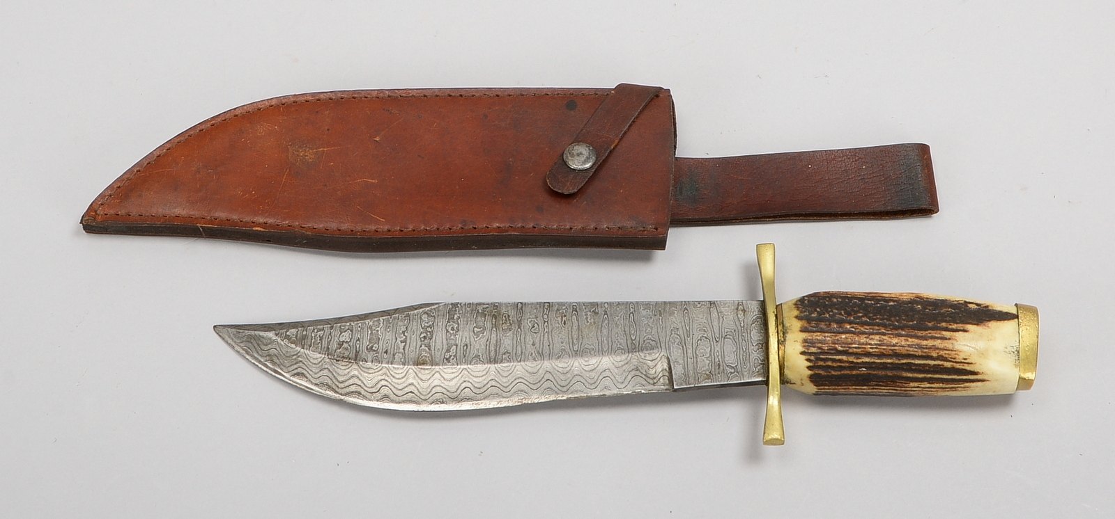 Bowie-Messer, Damasz. Stahlklinge, Horngriff, Messing-Parierstange, in orig. Lederscheide