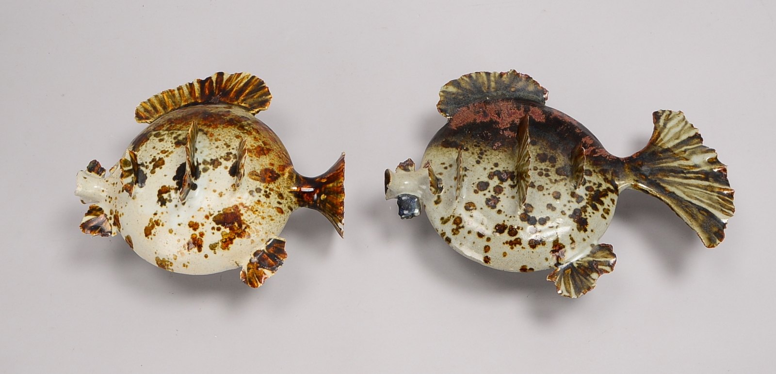 2 Künstlerkeramiken, 'Kugelfische', auf Eisensockel montiert; Höhe 15 cm/Höhe 18 cm