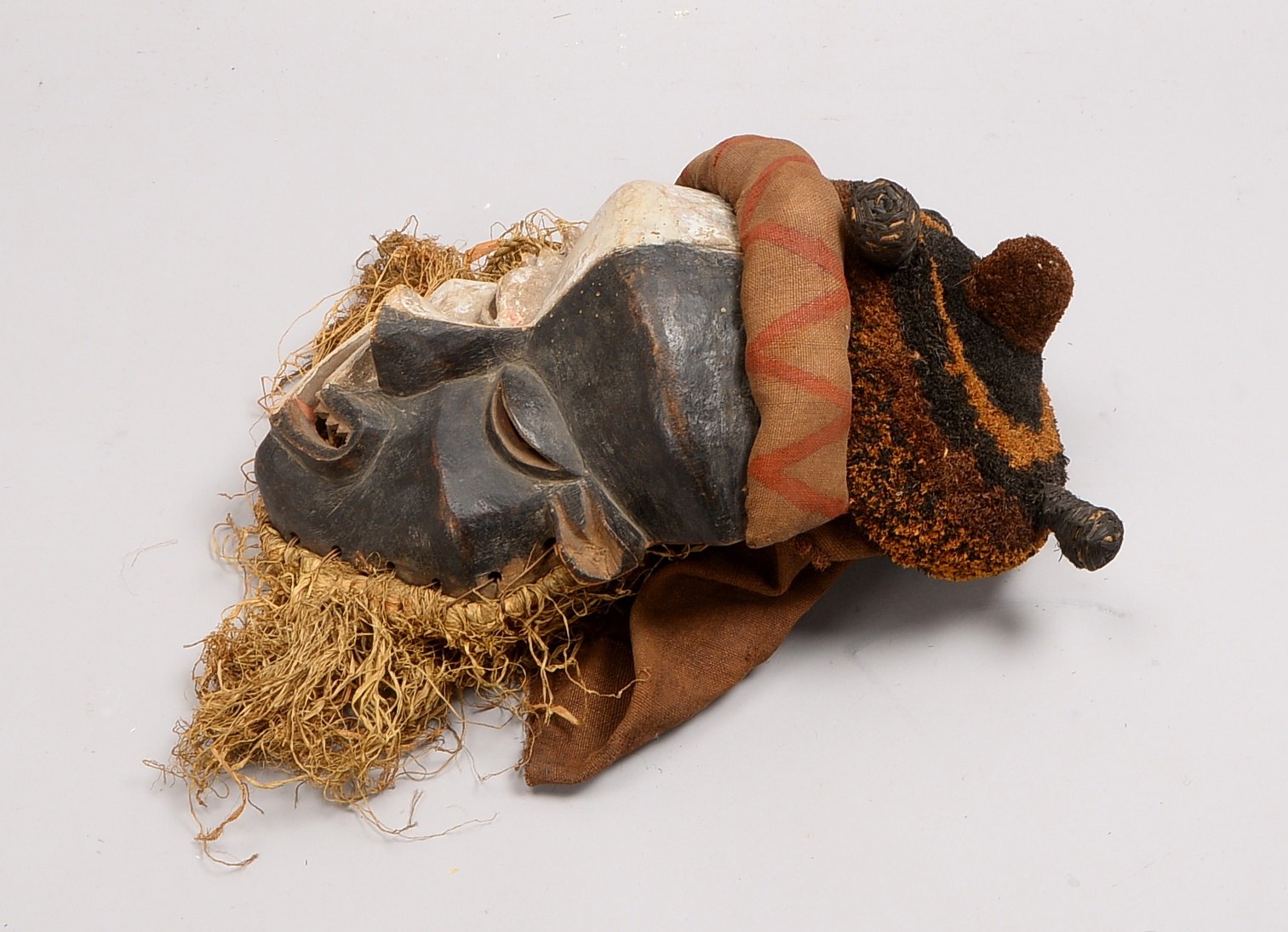 Ritualmaske (wohl Kamerun), Holz farbig gefasst, teils mit Stoff/Bast; Länge ca. 38 cm