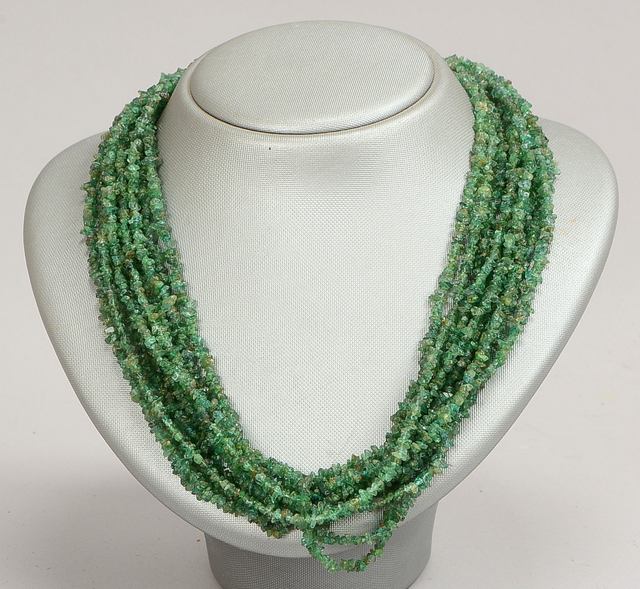Collier, 10-strängig, umlaufend mit Smaragdbesatz, unregelmäßige Steine/getrommelt, mit Silberschlie