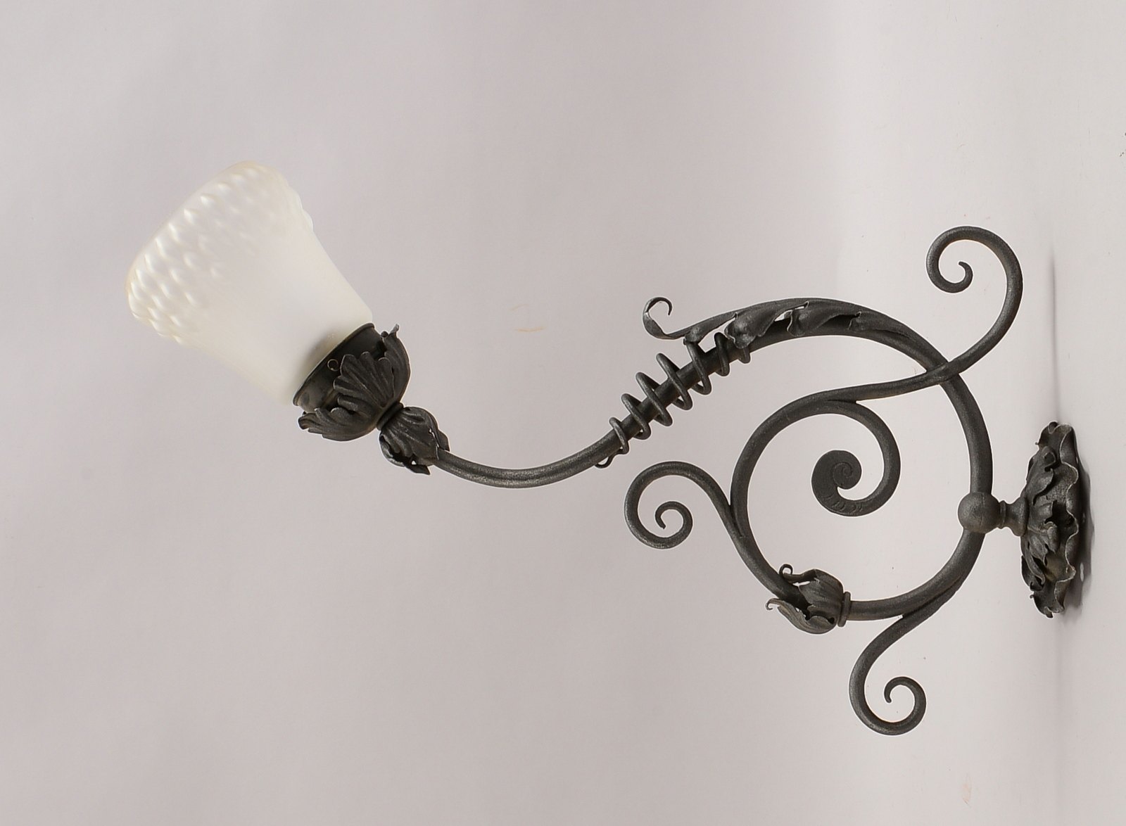 Wandapplikation, 1-flammig, Eisenguss, floral-ornamentale Ausführung, mit mattiertem Glasschirm - el