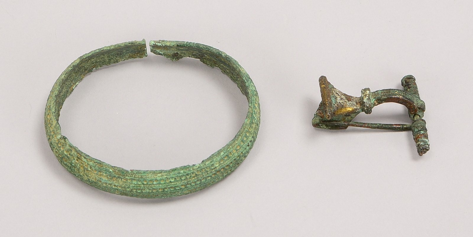 2 antike Ausgrabungen (Provenienz unbekannt), Bronze: 1 Armreif, und 1 Fibel