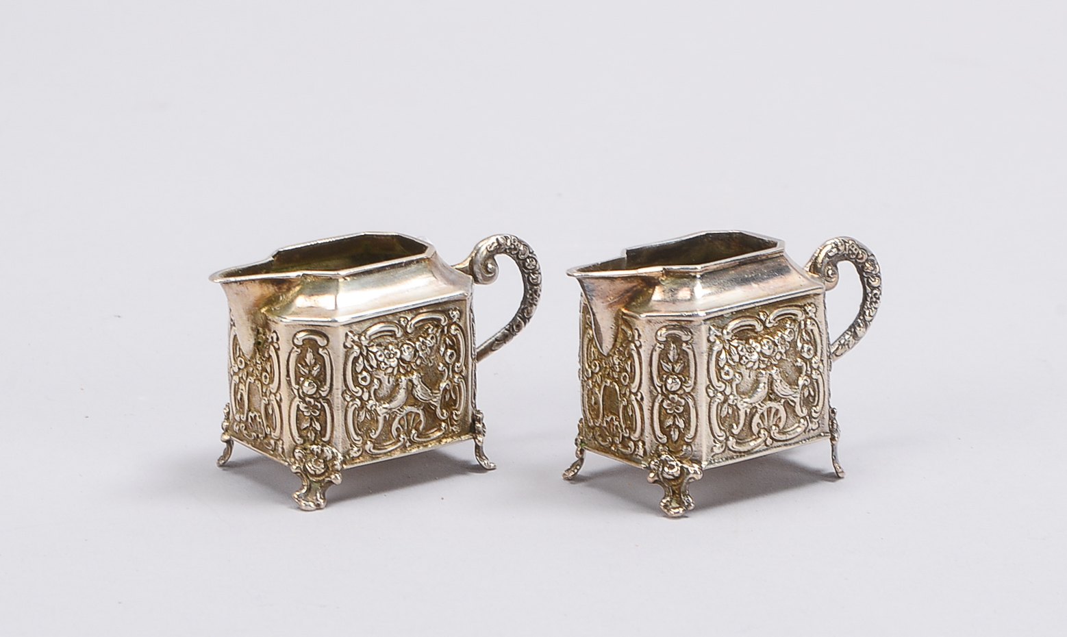 Paar Sahnegießer (deutsch), 800 Silber, barocke Ausführung mit floralem Reliefdekor, Korpus auf 4x V