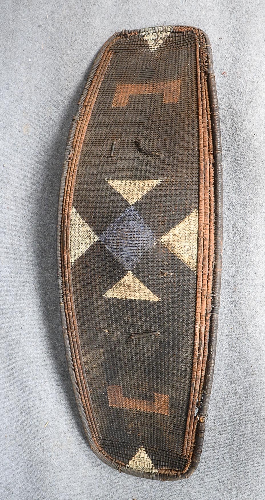 Ngombe-Kriegsschild, Kongo, Rattangeflecht, pariell geometrisch farbig gefasst, rückseitig mit Holzg