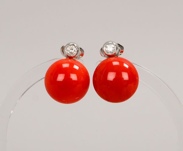 Paar Ohrclips, 750 WG (gest.), jeweils mit Korallencabochon und kl. Brillant; Gew. 8,80 g
