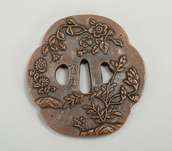 Bronze-Tsuba, Wandung mit floralem Reliefdekor und japan. Inschrift; Maße 8,5 x 8 cm