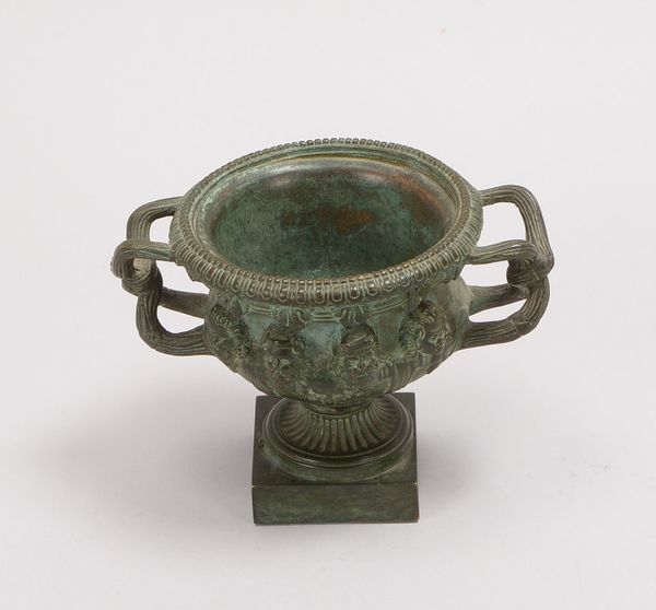 Kratervase, Bronze/grün pat., 8x plast. Köpfe, 2x Handhaben, Fuß gefüllt!; Höhe 9,5 cm